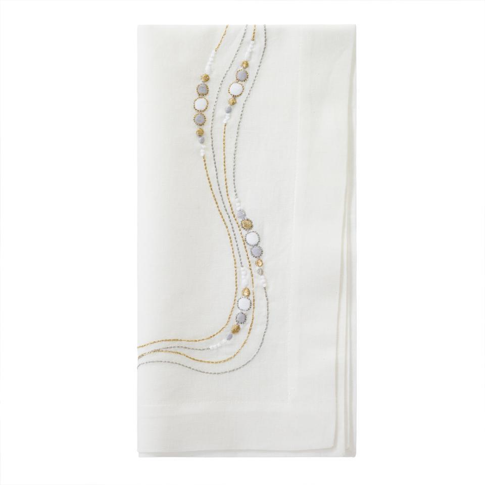 The Bodrum Drift Flow Napkin Gold & Silver Set of 4 features white cotton ramie napkins with elegant gold and silver embroidered lines and circles along one corner, shown on a plain white background.