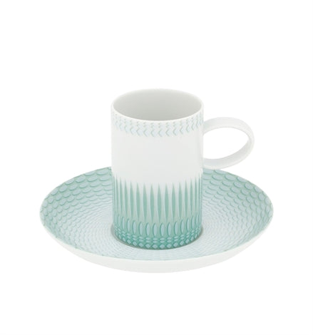 The Venezia Dinnerware coffee cup by Vista Alegre is a white porcelain piece with a handle, decorated with a light green geometric pattern, and comes with a matching saucer featuring the same design.