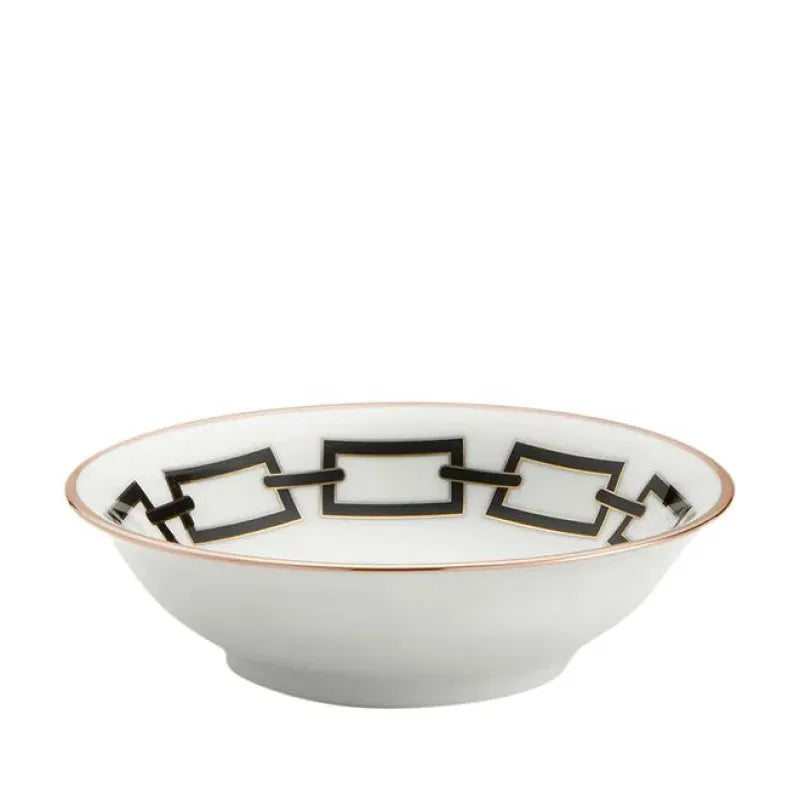The Catene Nero Dinnerware by Ginori 1735 features a white porcelain bowl adorned with a gold rim and a striking black geometric square pattern around the inner edge.