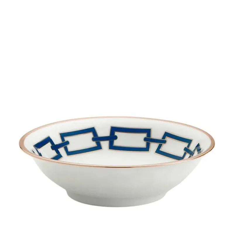 The Catene Zaffiro Dinnerware by Ginori 1735 features white porcelain with a gold rim and a geometric blue chain motif, inspired by Gio Ponti’s iconic designs.