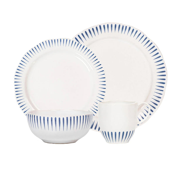 Certainly! Here’s a rewritten version using the product data: A set of four white ceramic dishes from Juliska’s Sitio Stripe Dinnerware - Delft Blue collection—a bowl, a mug, a medium plate, and a dinner plate—each adorned with vertical blue lines around the rim inspired by classic Delft blue design.