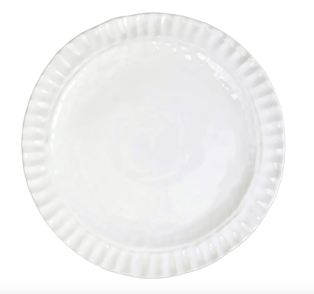 A white ceramic plate from Vietri’s Pietra Serena collection, featuring a gently scalloped, textured rim, shown from above on a white background.