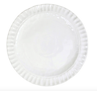 A white ceramic plate from Vietri’s Pietra Serena collection, featuring a gently scalloped, textured rim, shown from above on a white background.