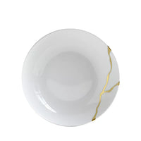 A white ceramic plate from Bernardaud’s Kintsugi Dinnerware collection, featuring gold lines reminiscent of kintsugi repair, viewed from above against a white background—an exquisite piece inspired by the artistry of Limoges, France.