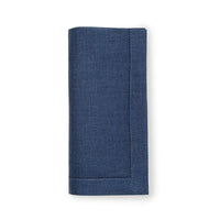 A neatly folded dark blue Festival Napkin from Sferra, featuring stitched edges, is positioned vertically against a plain white background.
