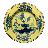 A round, yellow porcelain plate from the Ginori 1735 Oriente Italiano Dinnerware Citrino collection, featuring ornate blue chinoiserie floral motifs and geometric accents along the rim and center, reminiscent of classic Italian porcelain, viewed from above.