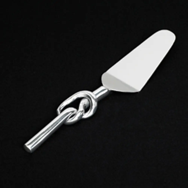 The Inspired Generations Knotty Cake Server features a modern stainless steel design with a shiny silver looped handle, shown against a black background.