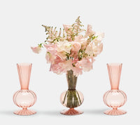 Three light pink, fluted, hand-blown glass Tess Bud Vase Set of 3 - Blush, one filled with a bouquet of pale pink flowers.