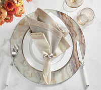 Elegant table setting featuring Kim Seybert’s Pearl Napkin Ring Grey & Silver Set of 4, marble-patterned charger plate, white china, beige and white napkins, silverware, two glasses, and orange flowers—perfect for sophisticated wedding decor.