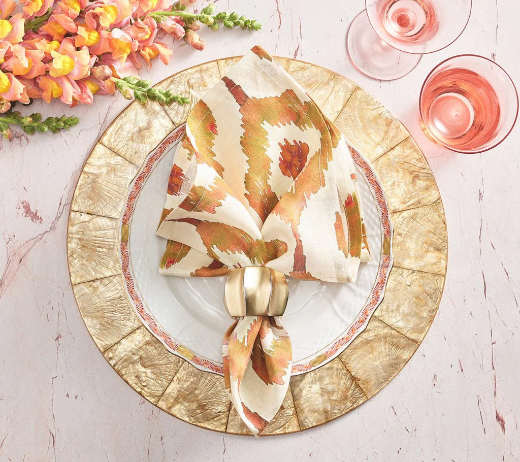 Elegant table setting with gold-rimmed plates, a patterned napkin held by the Kim Seybert Desert Napkin Ring Gold & Silver, pink flowers to the side, and two glasses of pink drink on a pale marble surface.
