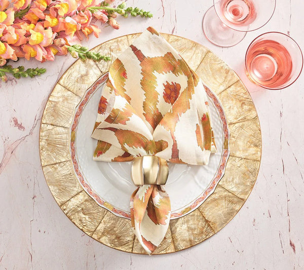 Elegant table setting with gold-rimmed plates, a patterned napkin held by the Kim Seybert Desert Napkin Ring Gold & Silver, pink flowers to the side, and two glasses of pink drink on a pale marble surface.