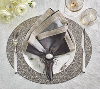 Elegant table setting featuring Kim Seybert Dip Dye Napkins - Earthtones (Set of 4), a marble-patterned plate, decorative napkin ring, silverware, two glasses, white flowers in the corner, and a textured tablecloth.