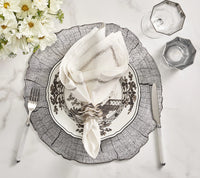 The Jardin Napkin Set of 4 by Kim Seybert is styled with a floral plate, silver-ringed napkin, white-handled fork and knife, two glasses, and a flower bouquet on a wood-patterned placemat atop marble.