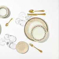 A formal table setting with Ginori 1735 Catene Cachemire Beige dinnerware, gold flatware, and clear glassware. Includes a dinner plate, salad plate, bread plate, and cups on a white background.