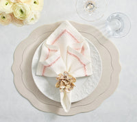 A dining table set with Kim Seybert's Tailored Placemat Set of 4 in Ivory, a textured white plate, folded napkin with pink embroidery, floral napkin ring, wine and water glasses, and a vase of cream-colored flowers.