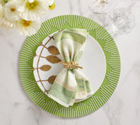 A white plate sits on a Kim Seybert Dream Weaver Placemat in Green & White, topped with a striped napkin in a gold ring. Gold utensils, glassware, and a floral arrangement are set nearby on the white marble table.