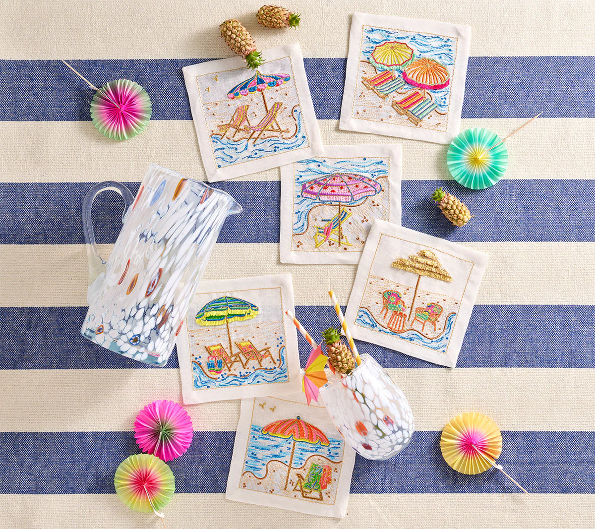 The Kim Seybert Cocktail Napkin Set of 4- Sunny Isles features colorful embroidery, perfect as linen hostess gifts. Pair with a patterned glass pitcher, matching glass, and vibrant paper drink stirrers for a cheerful setup.