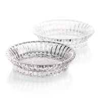 Two clear, round Mille Nuits Wine Coasters by Baccarat with intricate patterns are placed on a white surface, one slightly in front and overlapping the other.
