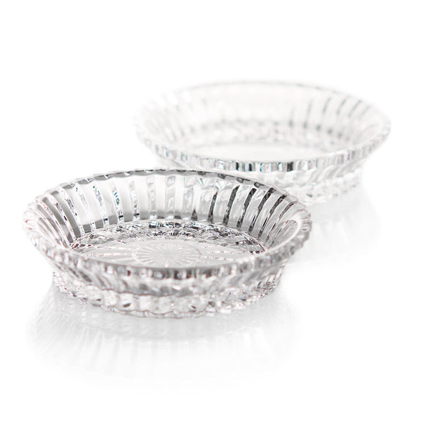 Two clear, round Mille Nuits Wine Coasters by Baccarat with intricate patterns are placed on a white surface, one slightly in front and overlapping the other.
