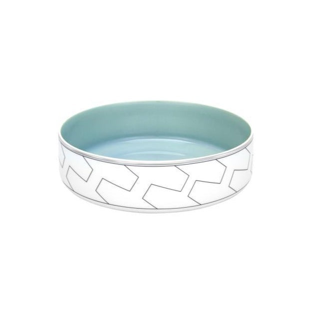 The Trasso Dinnerware by Vista Alegre is a round ceramic bowl featuring a light blue interior and a white exterior adorned with a geometric arrow design, inspired by elegant platinum-accented dinnerware.