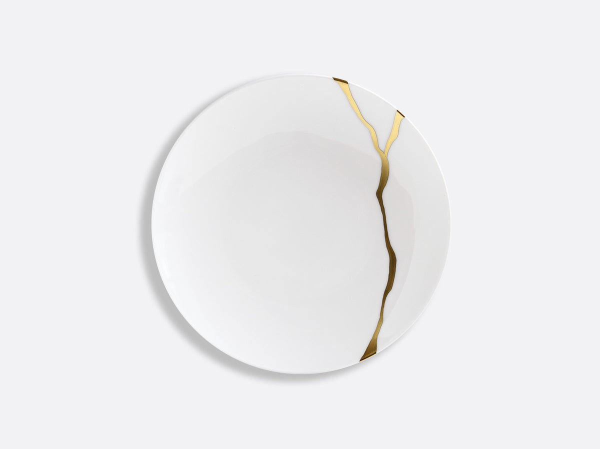 The Bernardaud Kintsugi Dinnerware features a white Limoges porcelain plate accented with a visible gold crack repair, inspired by the Japanese kintsugi technique, shown on a plain light gray background.