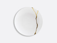 The Bernardaud Kintsugi Dinnerware features a white Limoges porcelain plate accented with a visible gold crack repair, inspired by the Japanese kintsugi technique, shown on a plain light gray background.