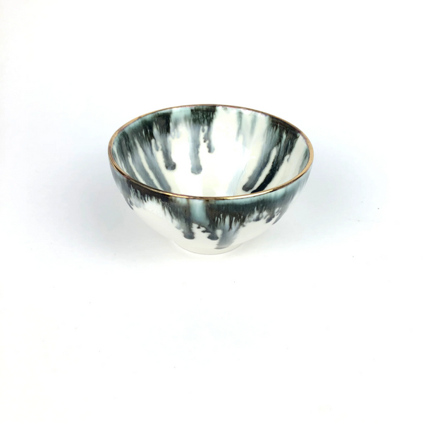 The Michael Wainwright Fjord Dip Bowl features a white ceramic base with dark green, black, and gray marbled glaze dripping from the rim, accented by a thin gold edge—an elegant touch for any modern table. Plain white background.