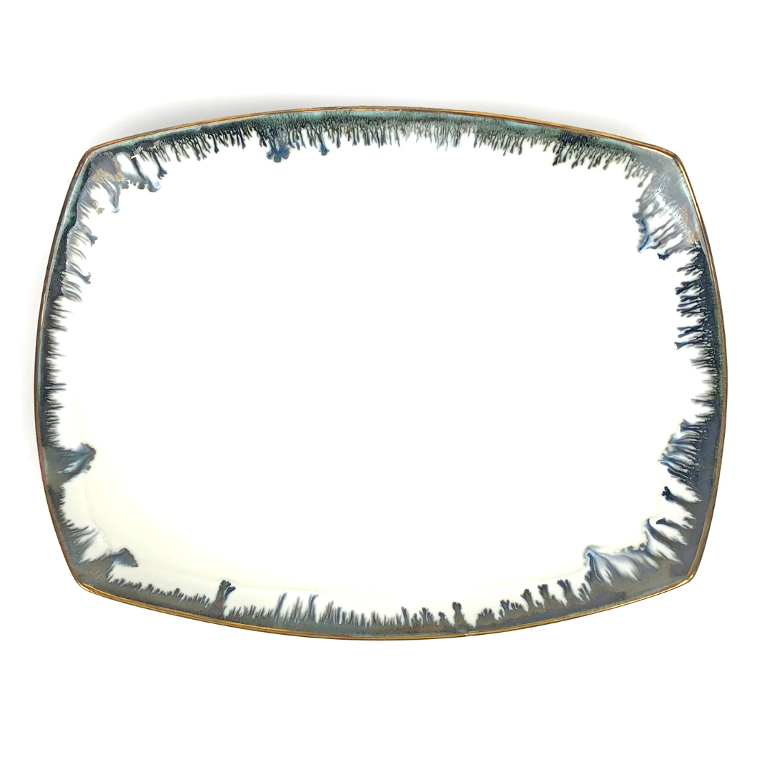 The Michael Wainwright Fjord Oval Platter - Large features slightly curved edges, a glossy white ceramic surface, and a dark blue abstract border, making it a striking piece for stylish serving.