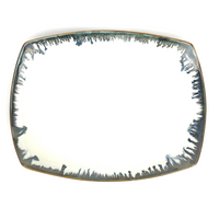 The Michael Wainwright Fjord Oval Platter - Large features slightly curved edges, a glossy white ceramic surface, and a dark blue abstract border, making it a striking piece for stylish serving.