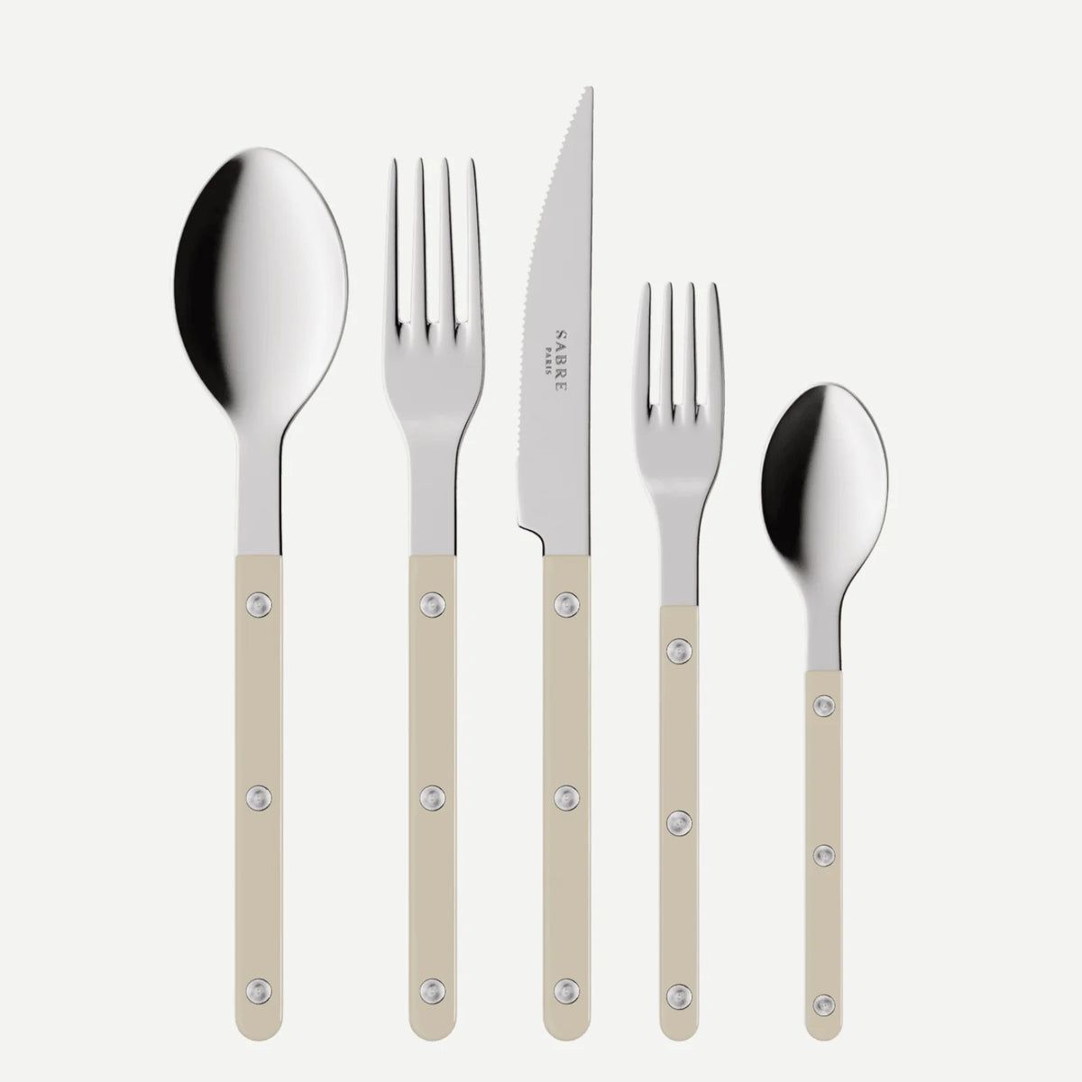 The Bistrot Solid Flatware 5 Piece Setting - Shiny by Sabre features beige-handled utensils—a large spoon, dinner fork, steak knife, salad fork, and small spoon—elegantly displayed side by side on a white background.