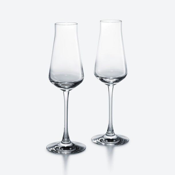 Two clear, empty Baccarat Chateau Barware crystal glasses with slightly flared rims stand side by side on a plain light gray background.