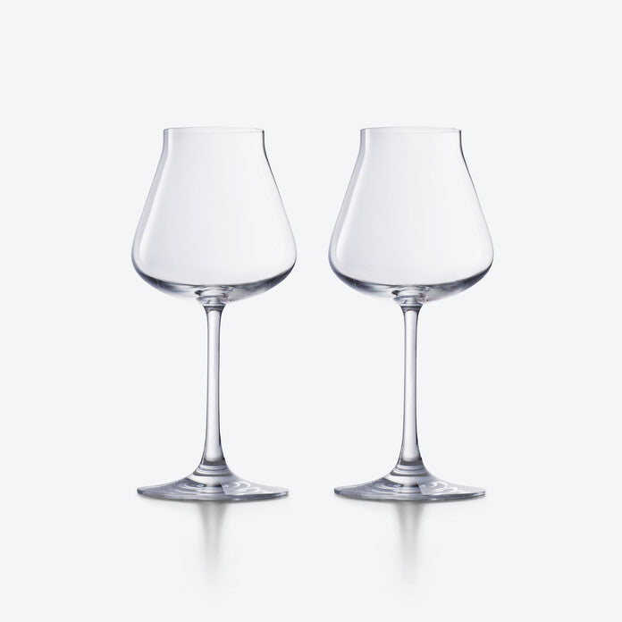 Two empty, clear Chateau Barware wine glasses by Baccarat, featuring wide bowls and slender stems, are placed side by side on a plain, light gray background.