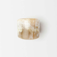 A wide, cylindrical beige ring with a smooth, marbled texture—this Blue Pheasant James Natural Horn Napkin Ring (set of 4) is crafted from natural horn and displayed against a plain white background.