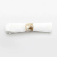 A white cloth napkin is neatly rolled and secured with a round, glossy James Natural Horn Napkin Ring by Blue Pheasant, set against a plain white background.