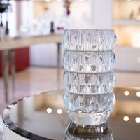 Clear 11″ Louxor Round Vase 230 by Baccarat with a faceted geometric pattern, sitting on a circular reflective table.