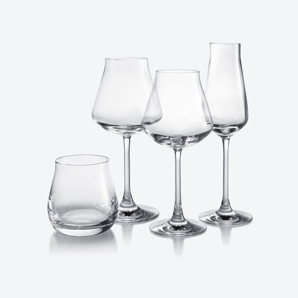 Four clear, empty Chateau Barware glasses by Baccarat stand on a white background—three elegant wine glasses and one shorter, stemless glass—evoking the timeless appeal of fine French crystal.