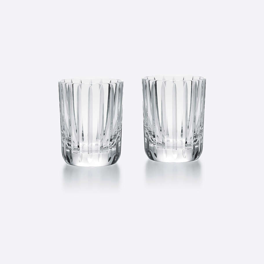 The Baccarat Harmonie Barware Set of 2 features clear highball glasses with vertical cuts, placed side by side on a light gray background, highlighting the refined modern design of these signature Baccarat glasses.