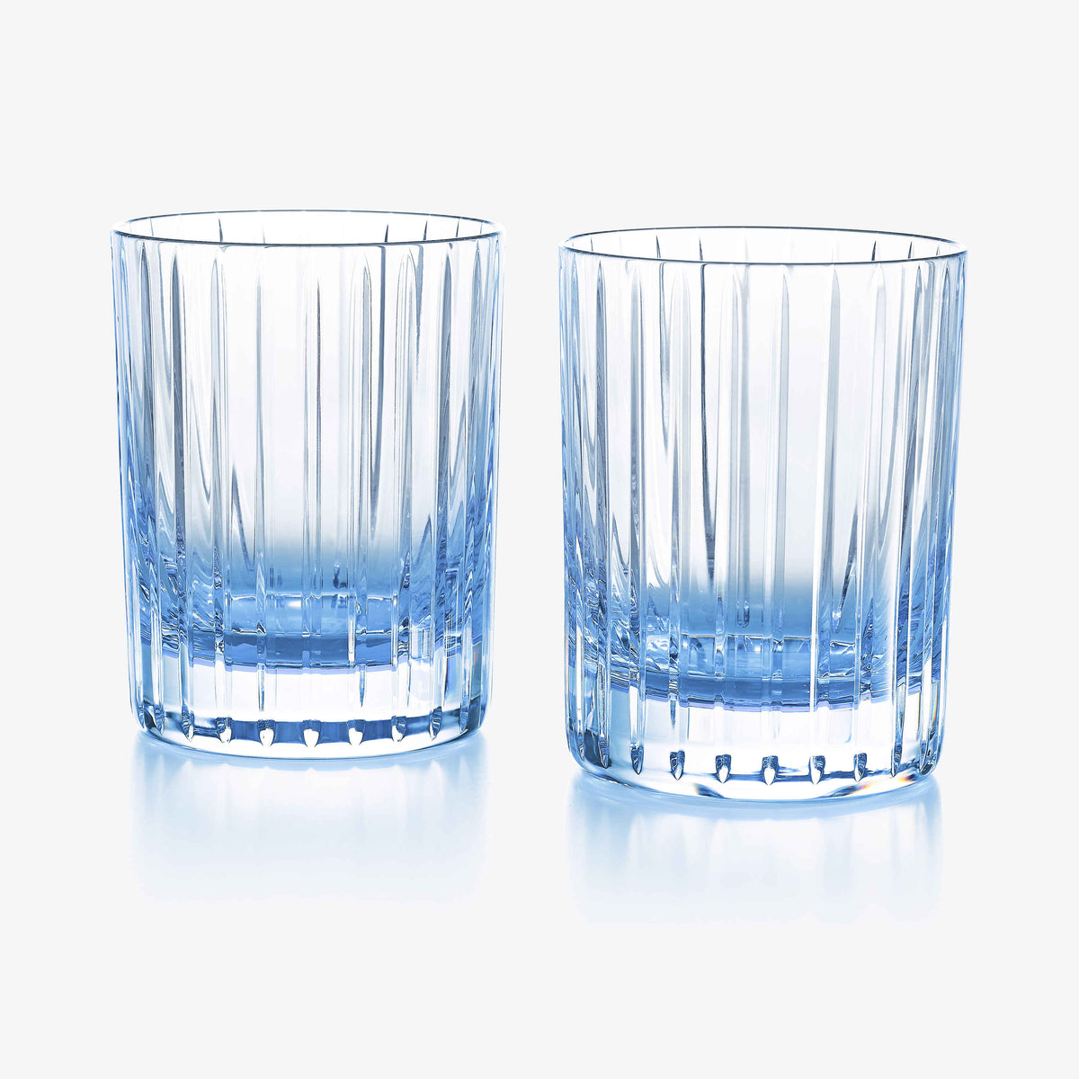 The Harmonie Colors of Joy Set of 2 in Pastel Blue by Baccarat features two crystal tumblers with elegant vertical ridges, perfectly paired side by side on a white background—an ideal stylish addition to your glassware collection.