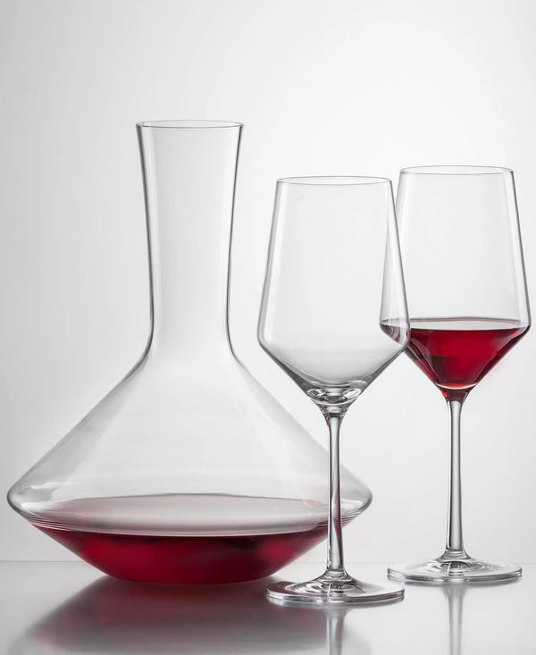 A Zwiesel Pure Red Wine Decanter filled with red wine, standing next to an empty wine glass and a glass partially filled with red wine.