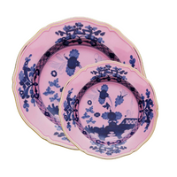 Two Oriente Italiano Azalea plates by Ginori 1735—stacked with the smaller on top—showcase a dark blue chinoiserie floral motif and gold-trimmed edges, bringing an elegant touch to your decor.