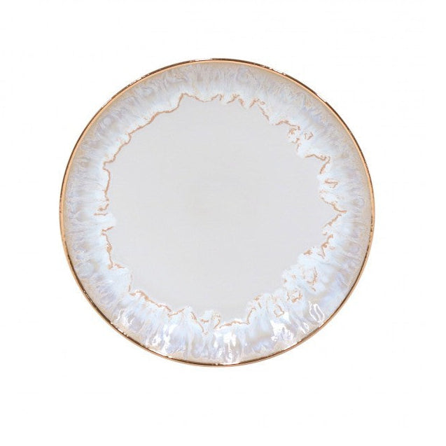 The Taormina Dinnerware White & Gold by Casafina/Costa Nova features a round ceramic plate with a white, subtly textured surface, an irregular stoneware edge, and a hand-painted 18-karat gold rim for an elegant marbled effect.