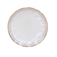 The Taormina Dinnerware White & Gold by Casafina/Costa Nova features a round ceramic plate with a white, subtly textured surface, an irregular stoneware edge, and a hand-painted 18-karat gold rim for an elegant marbled effect.