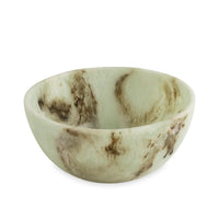 The Beatriz Ball Resin Giada Bowl Jade Swirl - Large features a round, shallow design inspired by jade, crafted in light green onyx-like resin with natural-looking brown and tan marbling patterns throughout its surface, showcasing a unique color pattern as it rests on a white background.