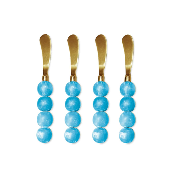 Set of four "Resin Sorbet Spreader Set of 4 - Blueberry" by Beatriz Ball, each featuring handles made from three round, glossy blue beads, arranged vertically side by side on a white background.
