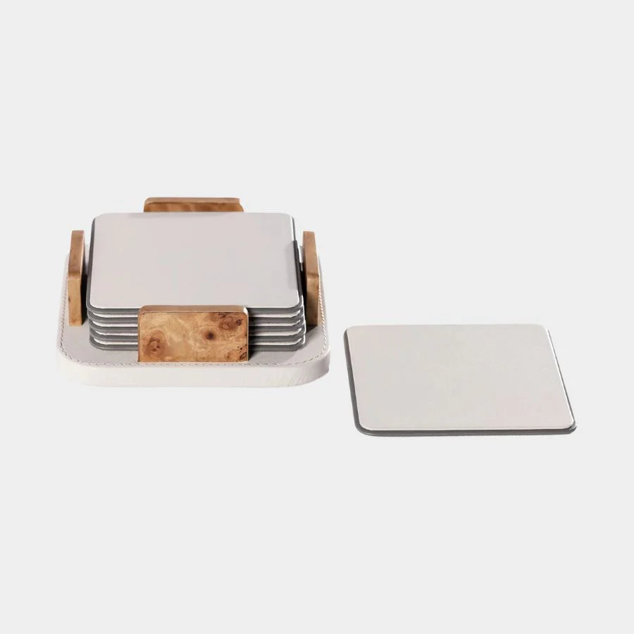 The Zodax Leather & Veneer Coaster Set - Ivory features six square, ivory coasters with a holder accented by wood, plus a single coaster displayed beside the set, all shown on a white background.