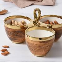 The PAMPA BAY Madera 3 Part Server features round porcelain bowls with wood-grain and gold accents, joined by a central handle—perfect for serving almonds and pistachios in style.