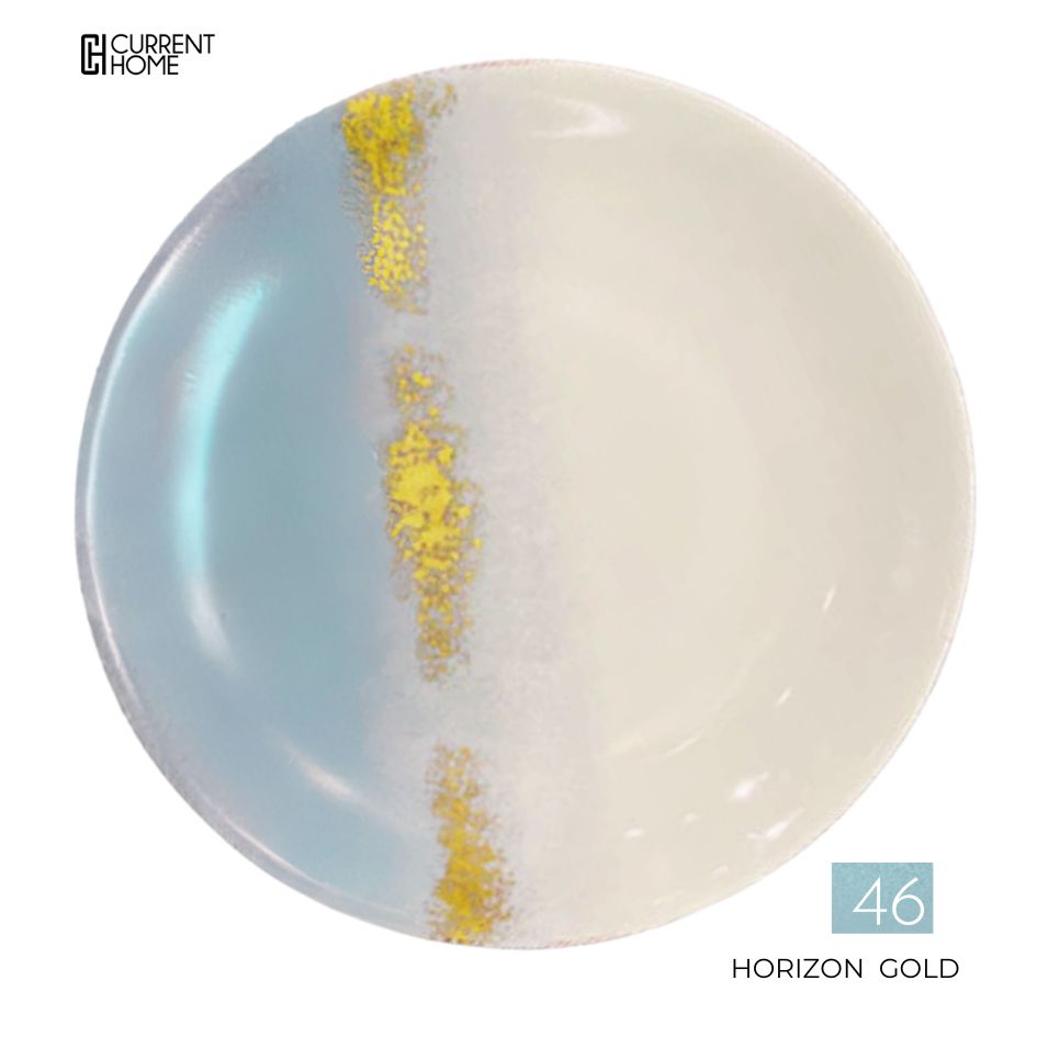 The Marie Daâge Horizon Gold Dinnerware features a round porcelain plate with a light blue-to-white gradient, a vertical gold and white speckled band, and the text "CURRENT HOME" and "46 HORIZON GOLD.