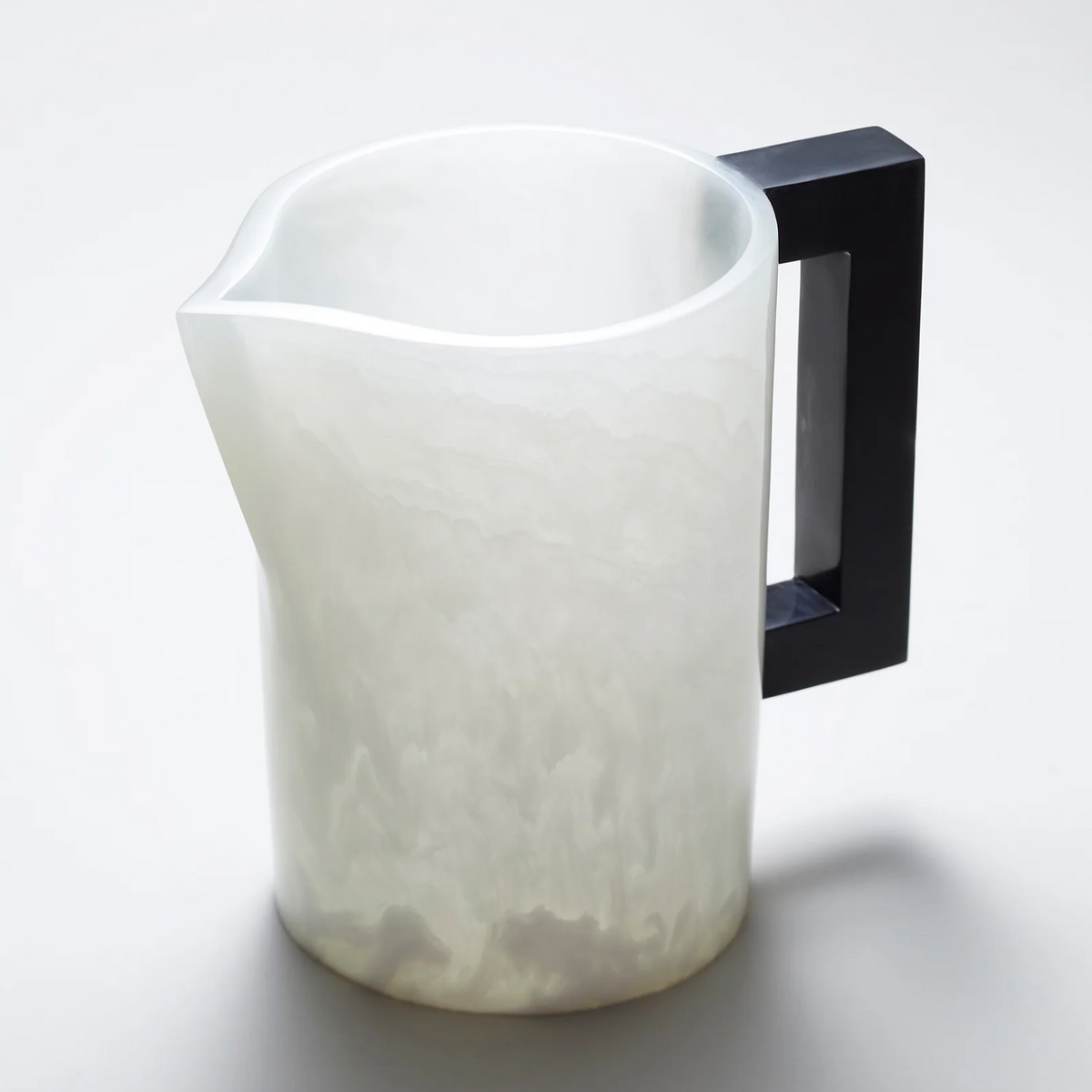 The Pearl's Pitcher White with Charcoal Handle by Lily Juliet features a translucent, marbled white resin body and a geometric black handle, offering modern elegance for dinner parties. Its matte finish sits beautifully on any light surface.