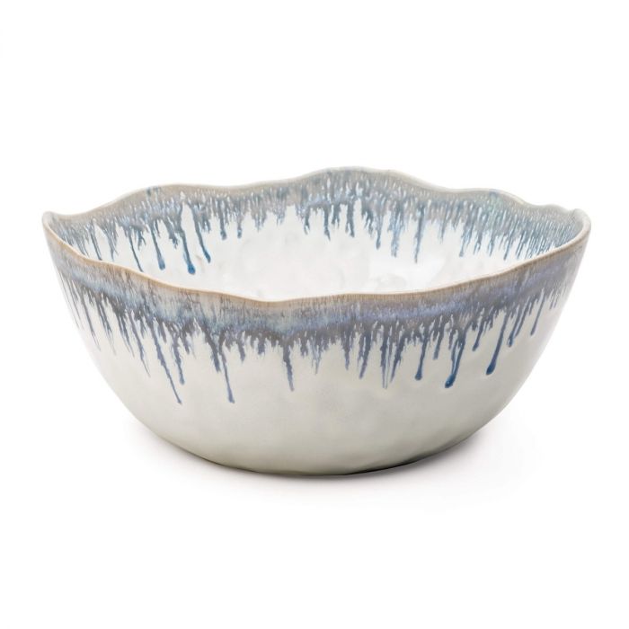 The Simon Pearce Burlington Dinnerware Pool bowl features a white ceramic base with wavy rim and blue glazed edge drips—a stylish, elegant addition to your collection.