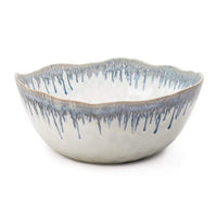 The Simon Pearce Burlington Dinnerware Pool bowl features a white ceramic base with wavy rim and blue glazed edge drips—a stylish, elegant addition to your collection.